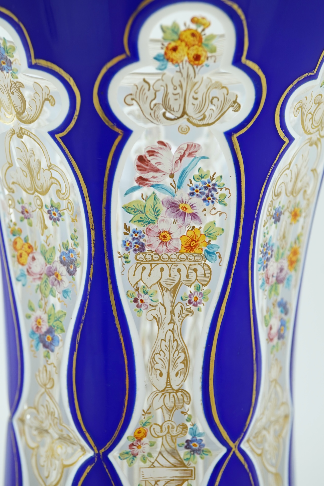 A tall 19th century Bohemian blue and white overlaid gilt and enamel decorated vase in the manner of Moser